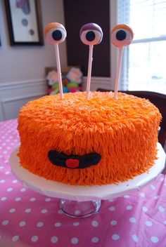 a cake with orange frosting and eyeballs on it sitting on top of a table