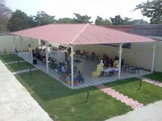 a group of people sitting at picnic tables under a red and white awning on the lawn