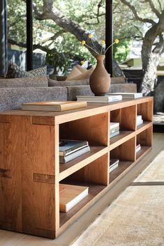 a living room with couches, bookshelves and a vase filled with flowers