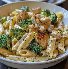 a white bowl filled with pasta and broccoli on top of a wooden table