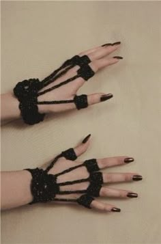 two hands with black nail polish and lace on them, one is holding the other