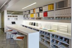 an office with white desks and shelves filled with folders