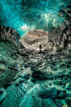 a man standing in the middle of a cave filled with rocks and green algaes