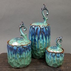 three pieces of blue and green pottery sitting on top of a wooden table