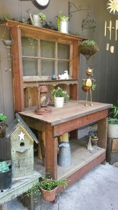 an old wooden hut with potted plants and birdhouses on the shelves in front of it