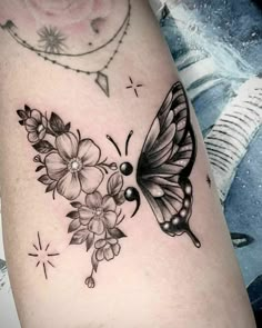 a black and white butterfly with flowers on it's arm, next to a tattoo