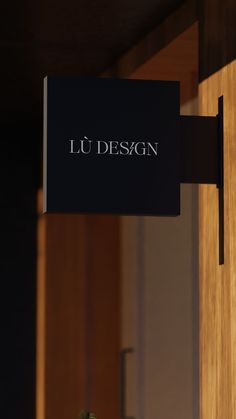 a black sign hanging from the side of a wooden door that says lu desagn