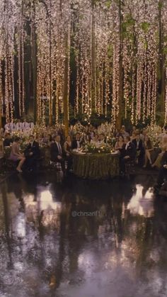 a group of people sitting around a table in the middle of a forest filled with flowers