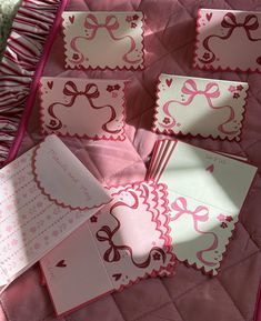 pink and white cards with bows on them are laying on a quilted bed spread