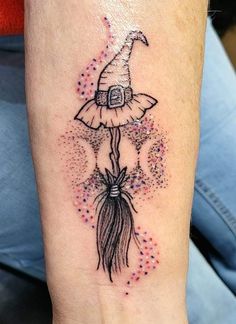 a tattoo on the arm of a woman with a wizard hat and feathered tail