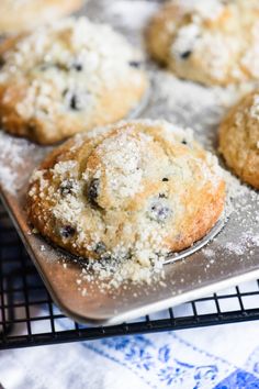 blueberry muffins are cooling on a baking sheet with powdered sugar sprinkled on top