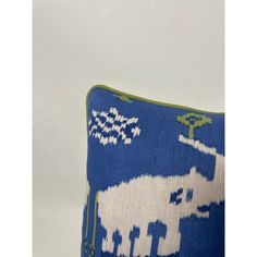 a blue and white pillow with an elephant design on the front, sitting against a white wall