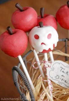 there are apples on top of the sticks in the cupcakes holder, which is decorated with white chocolate and red candies