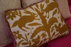 a close up of a decorative pillow on a couch with pink cushions and pillows behind it