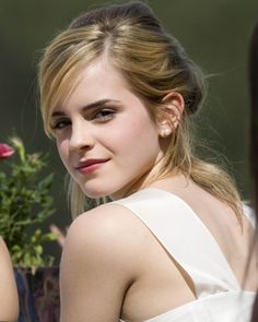 a young woman with blonde hair wearing a white dress and holding a flower in her hand