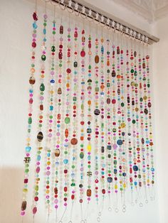 there is a wall hanging made out of many different colored beads and pins on it