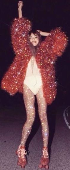 a woman is dressed in red and silver glitters while standing on the street with her arms up