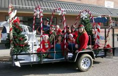 a group of people riding in the back of a truck with christmas decorations on it