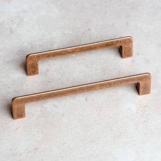 two brass drawer pulls on a white marble countertop, one has a metal handle