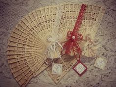 an old fan with tags attached to it sitting on a lace covered tablecloth,