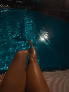 a person laying down in front of a swimming pool with their feet on the edge