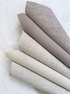 four different shades of fabric on a white surface with one grey and the other beige