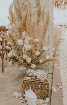 an arrangement of dried flowers and shells on the ground next to a basket with seashells