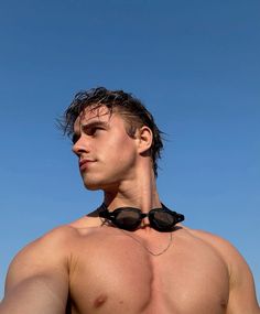 a man with no shirt wearing sunglasses on top of his head and looking off into the distance