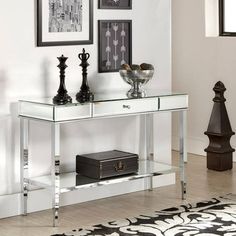 a mirrored console table with two vases and pictures on the wall in front of it