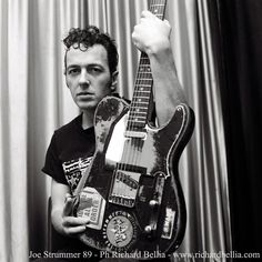 a black and white photo of a man holding an electric guitar in his right hand