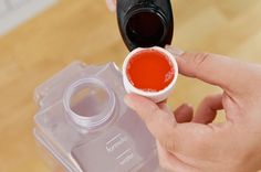 a person is holding a small container with red liquid in it