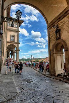 people are walking down the street under an archway