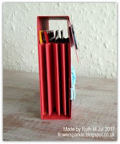 a red pen holder with pens and pencils in it