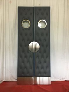 two metal doors with round knobs on each side and circular holes in the middle