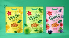 three bags of snacks sitting next to each other on a green surface with fruit in them