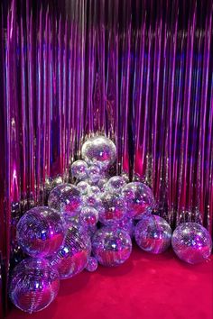 many shiny disco balls and streamers are on the red carpet in front of purple curtains