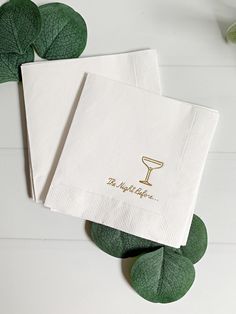 two white napkins with gold lettering on them