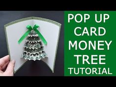 the pop up card money tree is being held by someone's hand with green ribbon