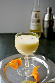 a glass filled with liquid sitting on top of a silver plate