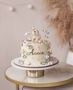 a white cake with pink flowers and an animal on top