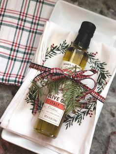 a bottle of olive oil sitting on top of a white plate next to napkins