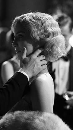 black and white photograph of a woman talking on the phone with a man standing behind her