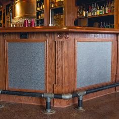 an empty bar with lots of bottles on the shelves and behind it is a metal pipe