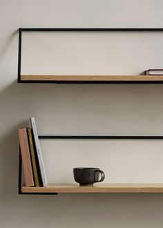 two shelves with books and a cup on them