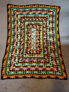 a multicolored rug is laying on the floor with it's edges crocheted