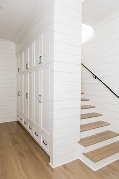 an empty room with white painted walls and wooden stairs leading up to the second floor