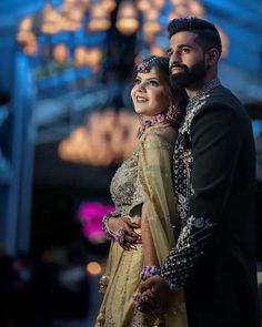 a man and woman standing next to each other in front of a chandelier