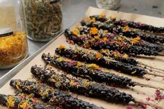 several sticks are lined up on a table with dried herbs and spices in the background