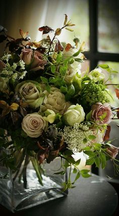 a vase filled with lots of flowers sitting on top of a table next to a window