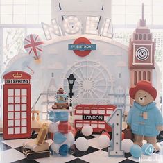 there is a large teddy bear in front of the london sign and some toys on the floor